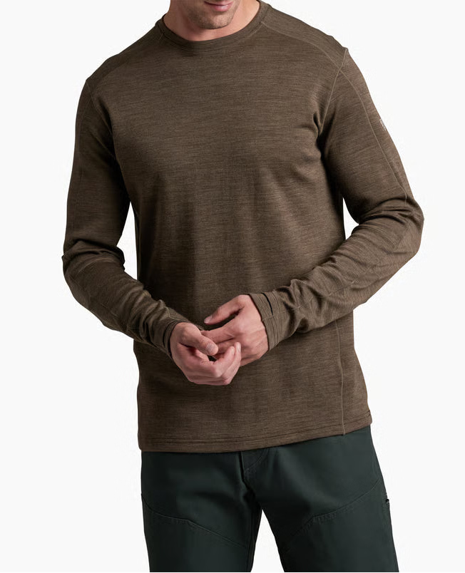 Man wearing a brown long-sleeve shirt and dark pants on a white background